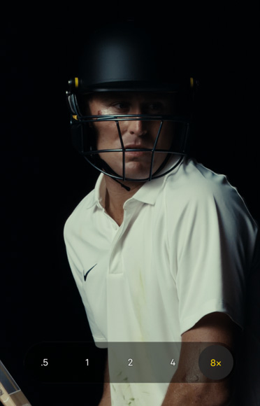 Zoomed-in close-up of cricketer Marnus Labuschagne wearing a cricket helmet and white shirt against a black background. Zoom slider is set to 8x, demonstrating clear definition at any zoom range.