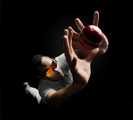 Cricketer Scott Boland, wearing reflective wraparound sunglasses and reaching up with both hands outstretched to catch a red cricket ball. Shot from above and at an angle, demonstrating how iPhone 17 Pro captures detailed action at any zoom level.