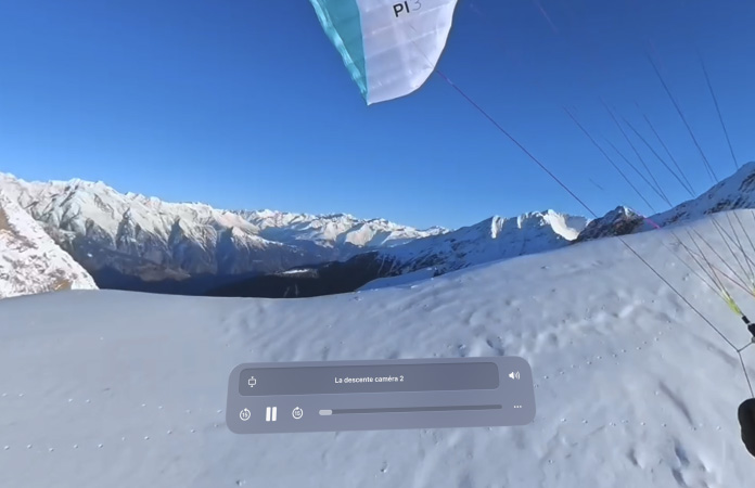Une personne fait du paraski dans les airs au-dessus du sommet d’une montagne en champ de vision large