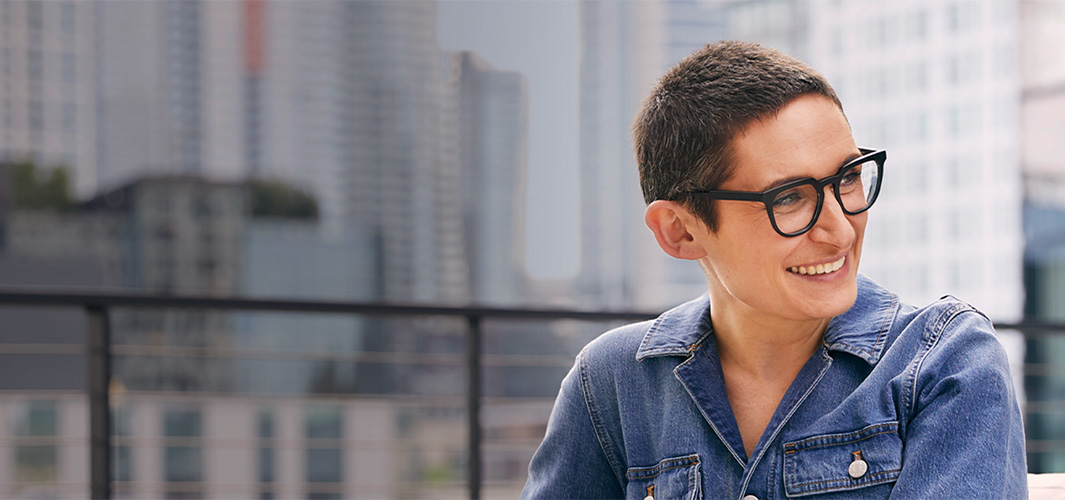 صوفي جالسة تتأمل المنظر المطل على المدينة وهي تبتسم وتنظر إلى الجانب.