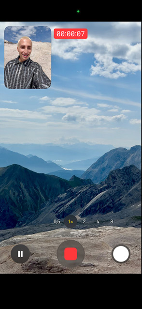 Eine Person zeigt die Funktion „Doppelte Aufnahme“, indem sie sich mit der Frontkamera und gleichzeitig die Berge mit der Rückkamera aufnimmt