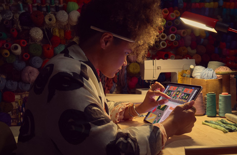 Työpöydän ääressä istuva henkilö zoomaa iPadin näytöllä olevaa kuvaa kahdella sormella.