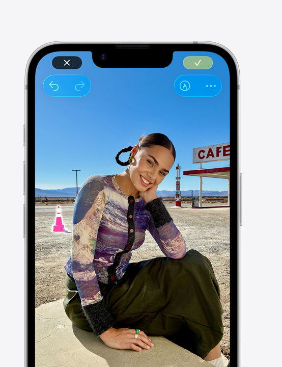 ビーチで微笑む人物の写真が表示されたiPhoneの画面。クリーンアップツールを使って背景にあるコーンを削除する方法を示している