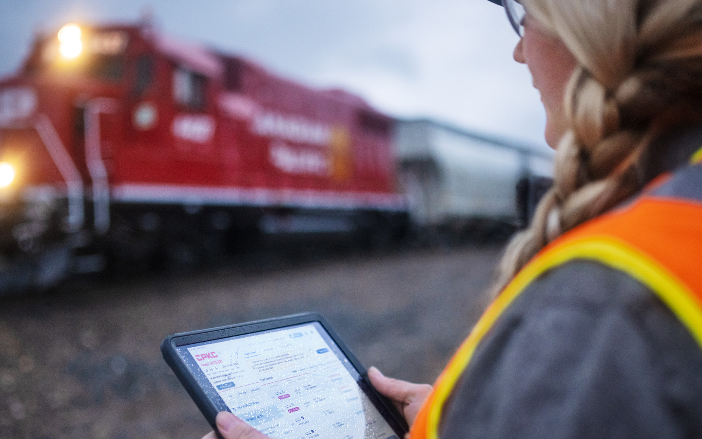 A railroad worker assesses train schedules on iPad while standing in the train yard
