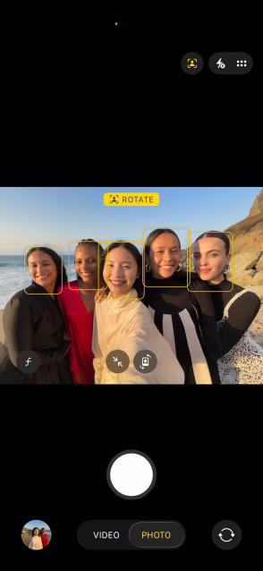 iPhone Air priekšējais ekrāns, kurā redzams grupas selfijs ar Center Stage fotografēšanas funkciju