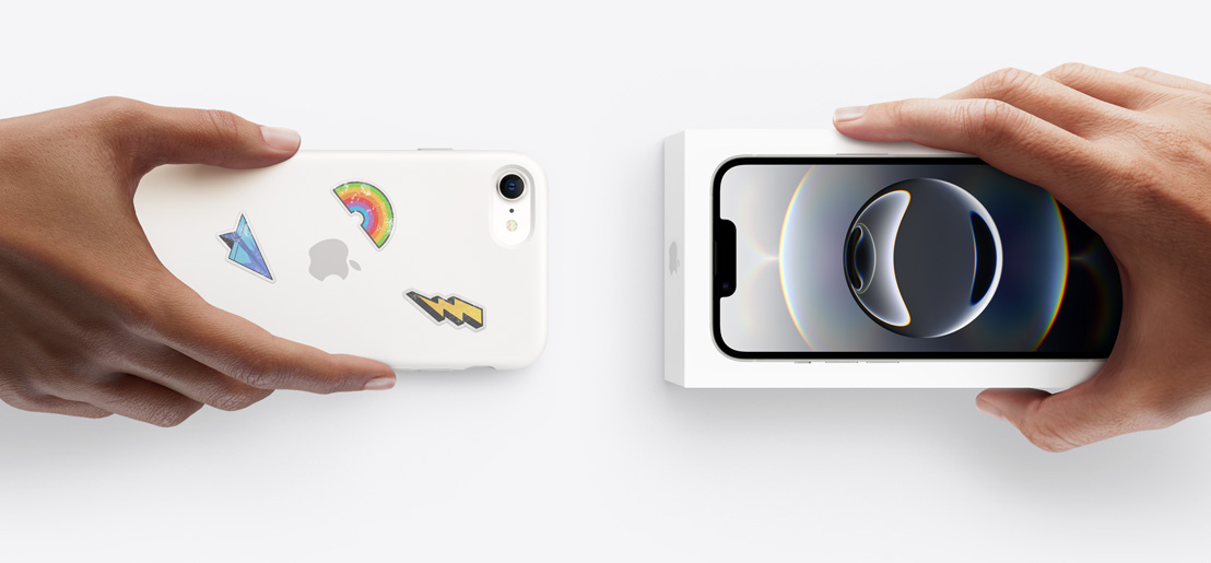 Una mano sostiene un iPhone 16e en una carcasa de silicona con stickers en la parte trasera para intercambiarlo por el nuevo iPhone 17, que está dentro de su caja, sostenida por otra mano.