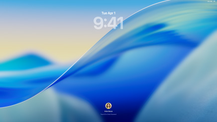 Trois modèles de Mac alignés orientés vers l’avant s’éloignent lentement les uns des autres, un MacBook Pro 16 pouces argent à gauche avec l’app Téléphone à l’écran montrant des contacts récents, un iMac 24 pouces bleu au centre, une vague du fond d’écran macOS Tahoe se déplace à l’écran, un MacBook Air 13 pouces minuit à droite, l’écran montre une recherche Spotlight sur le bureau avec le Dock et divers widgets tels que Calendrier, Horloge et Météo affichés en Liquid Glass