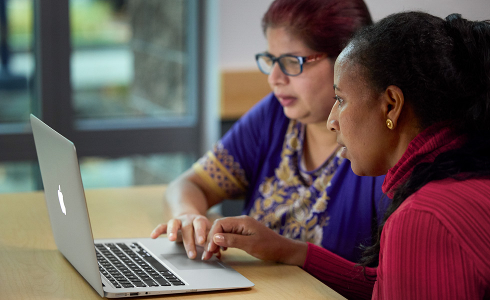 Two people share a laptop, collaborating or learning